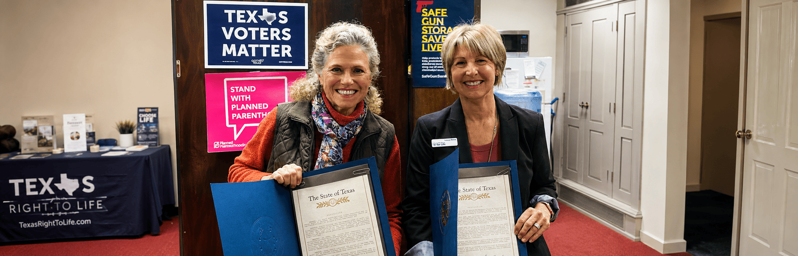Firearm safety advocates holding Texas Senate proclamations at a community event