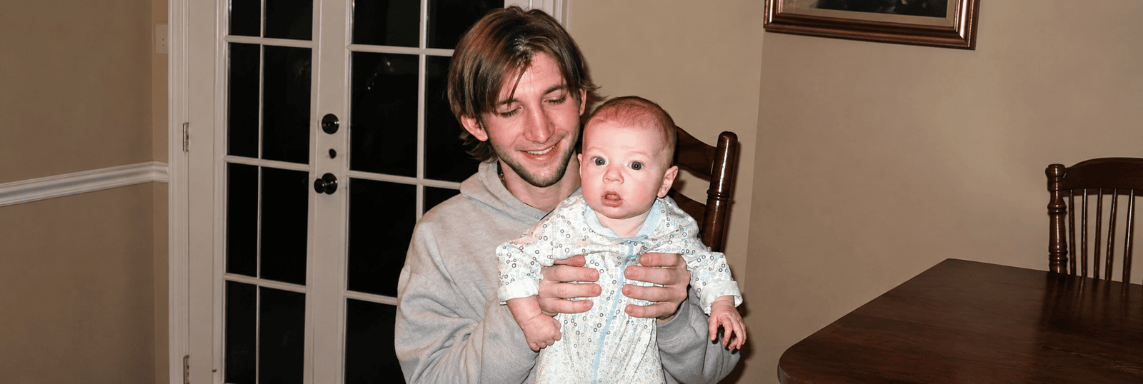 Jon holding a baby during a family gathering